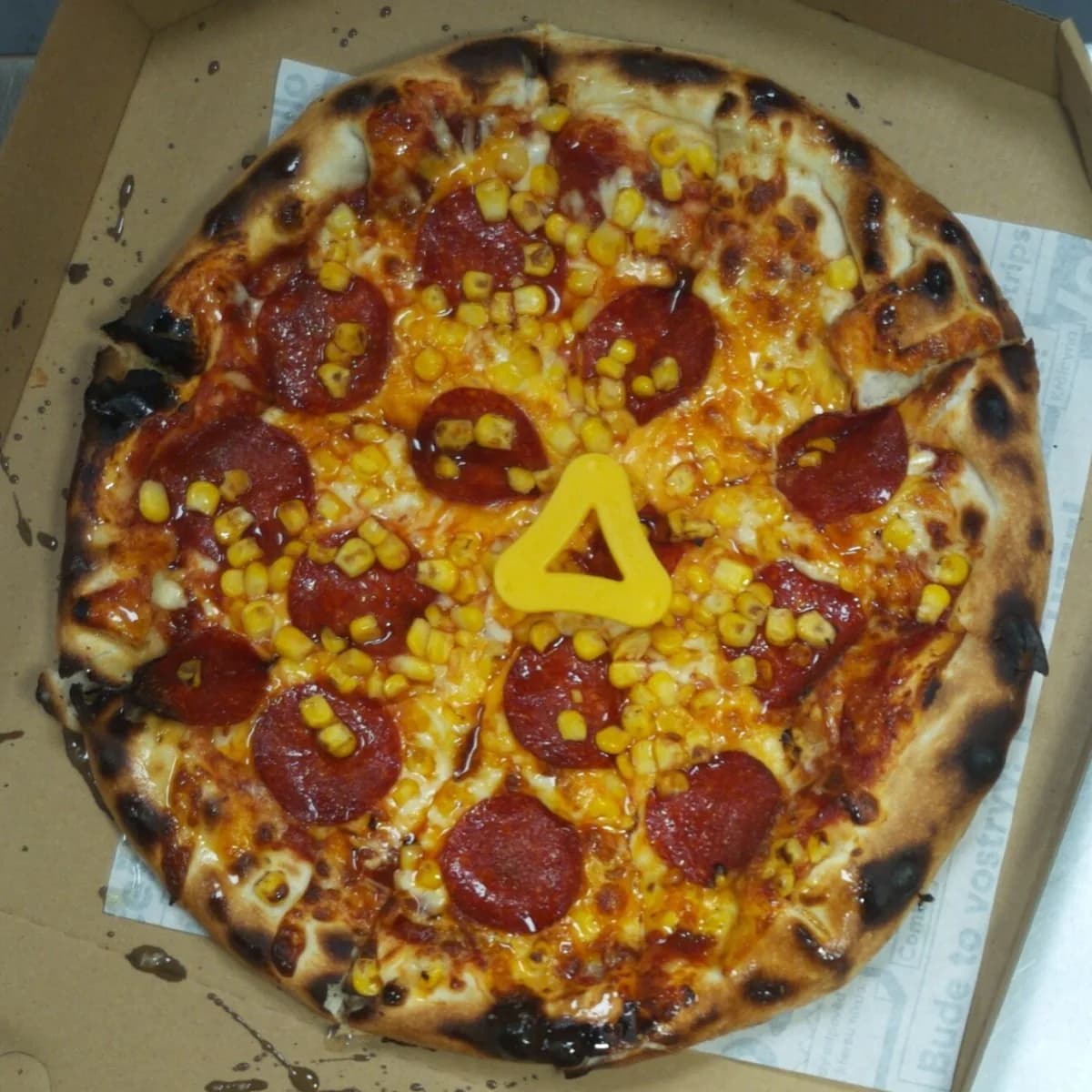Pepperoni and corn pizza with a charred crust